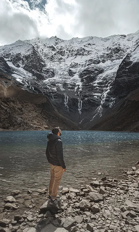 "A man admiring the mountains at the turqueise waters at Humantay Lake"