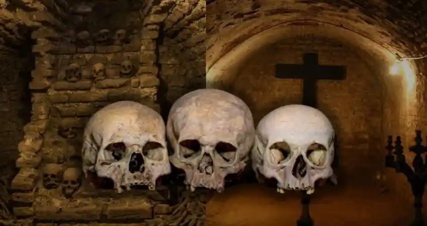 Three skulls in a cave with a cross in the background, depicting the Catacombs of Lima, Peru.