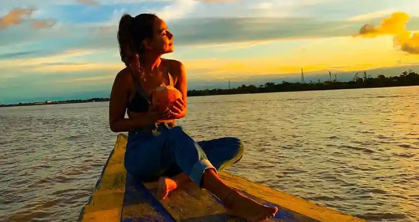 A woman sitting on a boat in the water, enjoying a scenic tour in Iquitos