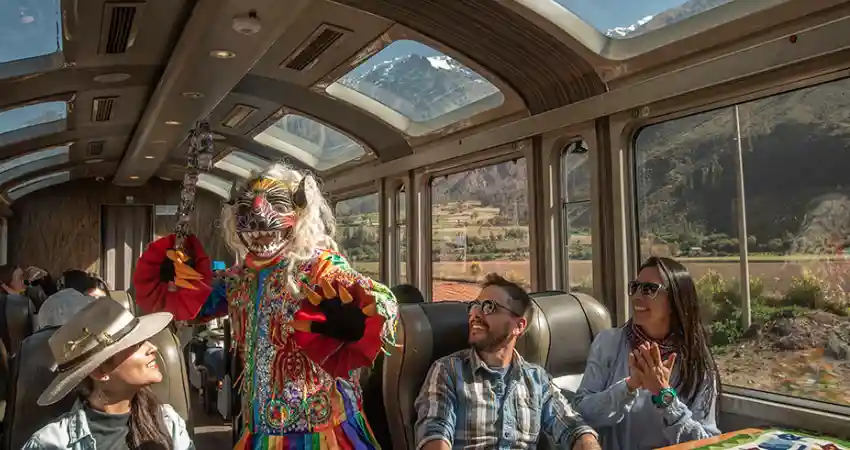 A colorful train to Machu Picchu from Sacred Valley, featuring a clown at the front, with passengers visible inside.