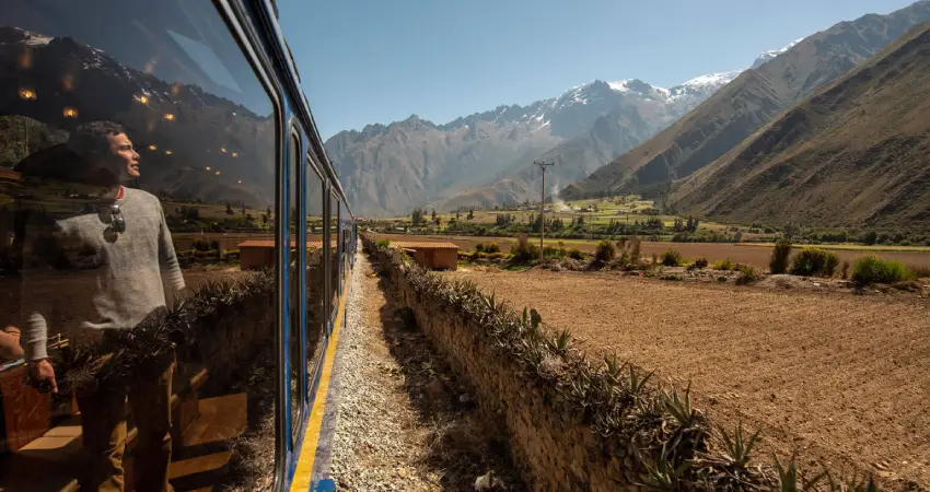 A man gazes out the train window, overlooking the mountains on the journey to Machu Picchu from Sacred Valley.