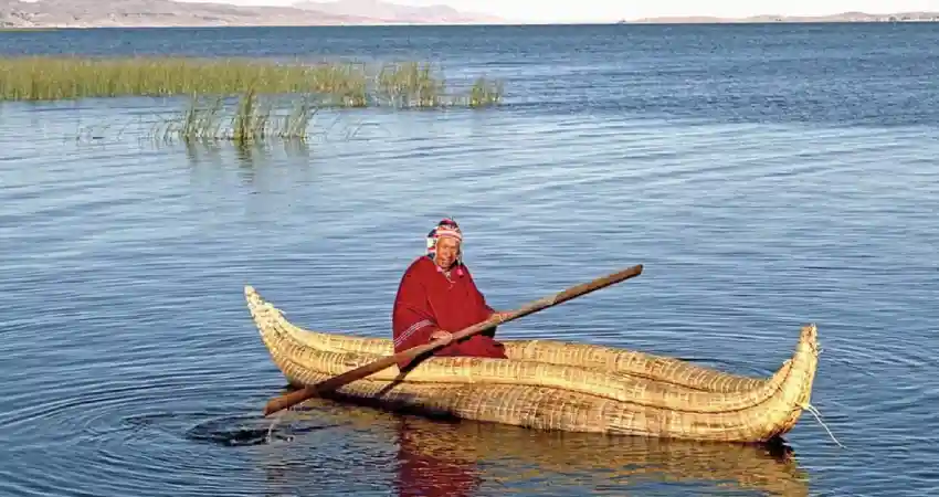 A man paddles a canoe on Lake Titicaca during a scenic boat tour.