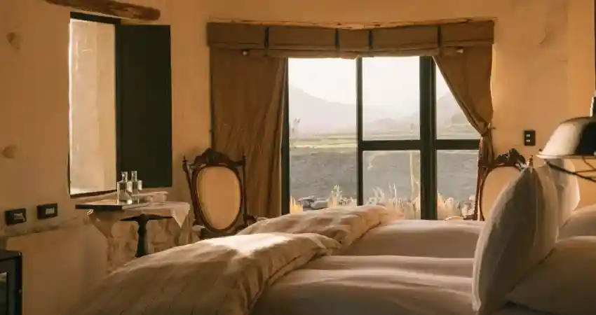 A cozy bedroom featuring large windows that showcase a stunning view of the mountains in Puqio.