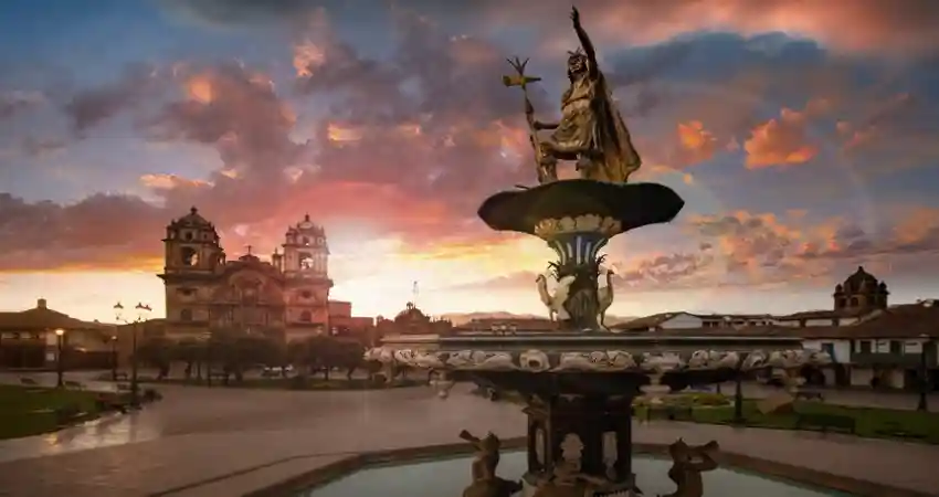 A fountain with a statue in front of a church, highlighting a notable point of interest in Cusco.