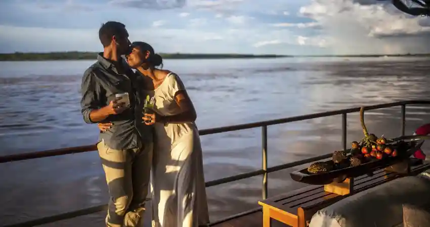 A couple enjoys a romantic boat ride on a river, surrounded by the scenic beauty of Peru during their luxury honeymoon.