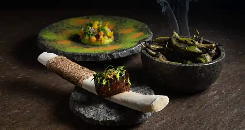 A bowl of food with a stick and knife, presented at Mayta Restaurant in Lima.