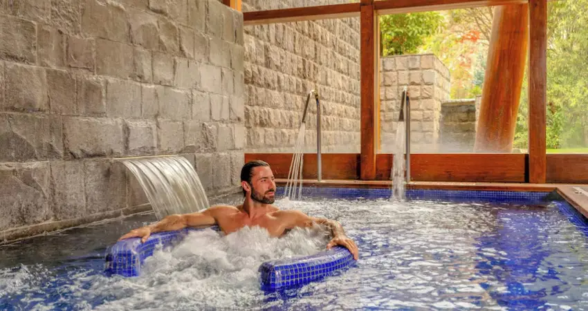 A man relaxes in a hot tub at Tambo del Inka resort in the Sacred Valley, surrounded by scenic views.