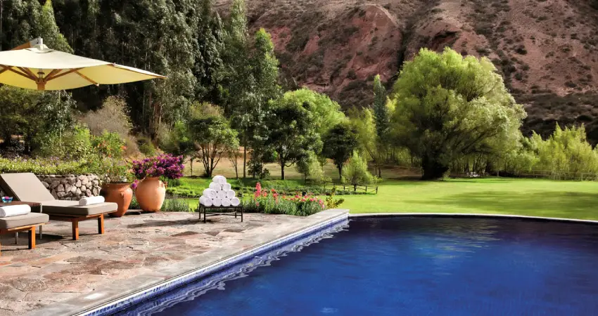 A serene pool with lounge chairs and umbrellas, set against the backdrop of mountains at Belmond Rio Sagrado, Peru.