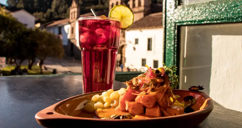 A plate of ceviche and a drink on a table, showcasing the best ceviche from Cusco.