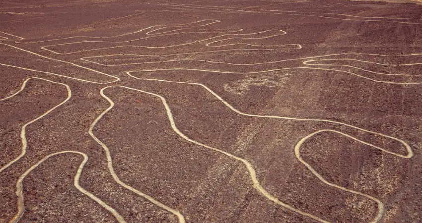 A vast desert landscape featuring intricate lines, illustrating the Nazca Lines, with a context of travel from Cusco.