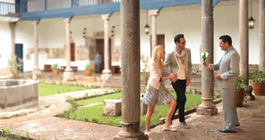 Three people stand in a courtyard at Palacio Nazarenas, a Belmond Hotel in Cusco, with a fountain in the background.