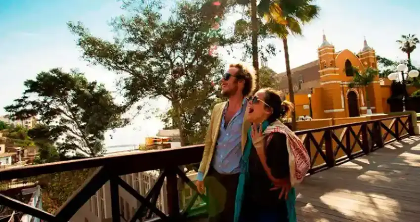 A man and woman stand on a bridge, gazing at the ocean during a luxury vacation in Peru.