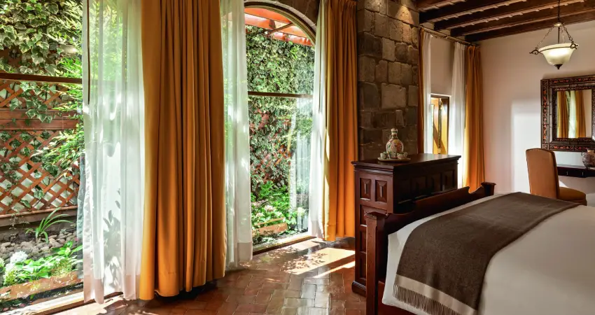 A spacious bedroom at Monasterio a Belmond Hotel Cusco featuring a large bed and a bright window.