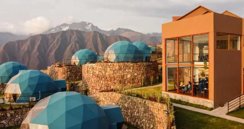 A house with blue domes perched on a hill in the Aranwa Sacred Valley, surrounded by lush greenery.