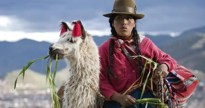 A woman with a llama in Cusco, Peru, showcasing the weather in May.
