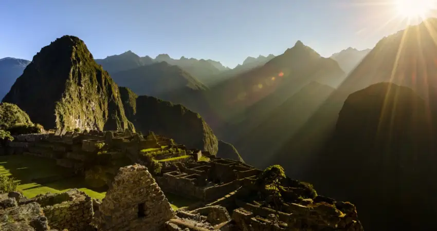 Sunrise over Machu Picchu in July with mountains in the background.