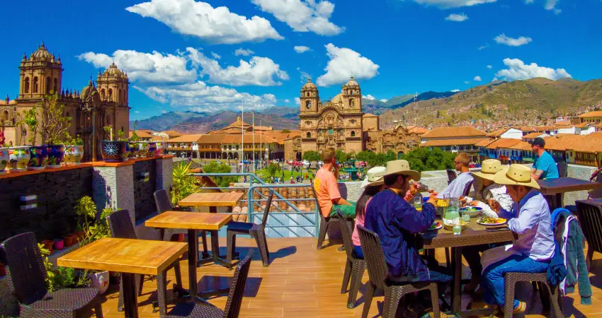 People sitting at tables on a rooftop, enjoying views, ideal for visiting the Best restaurants in Cusco.