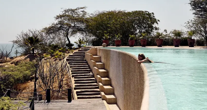 A woman sits at the edge of a large pool, enjoying the Best beach resorts in Peru.