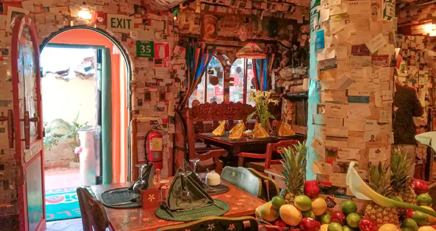 Colorful interior of Indio Feliz Restaurant in Machu Picchu, featuring a table and chairs set for dining.