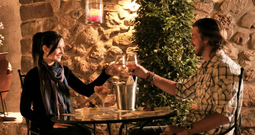 A man and woman toast with wine glasses in a restaurant, enjoying the vibrant nightlife of Machu Picchu.