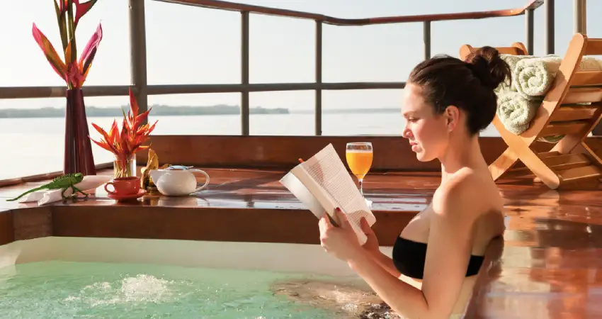 A woman relaxes in a hot tub, reading a book, showcasing a luxurious vacation experience in Peru.