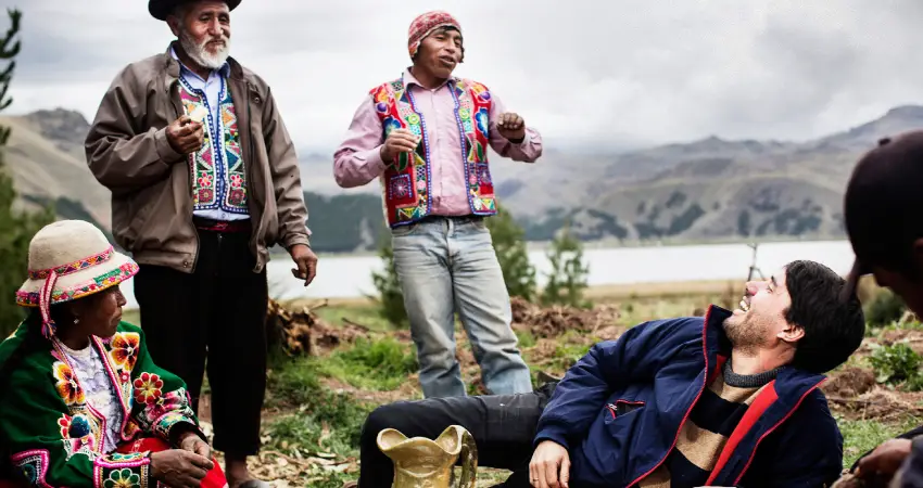 A group of individuals in traditional attire seated on the ground, engaged in conversation or sharing a moment together.